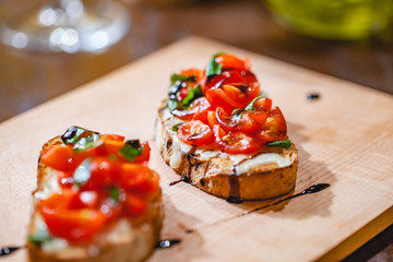 Traditional Italian bruschetta with cherry tomatoes, cheese, basil and balsamic vinegar on wooden...