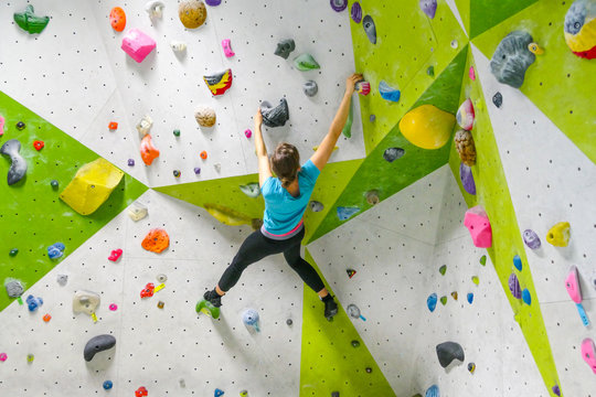 junge sportliche Frau beim Bouldern in Kletterhalle