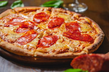 Italian Pepperoni pizza with mozzarella cheese and salami on wooden board. Close up