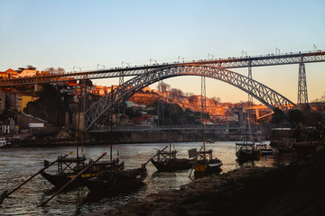 ponte luis i bridge in porto, portugal, at sunset with blue sky and port wine boats in foreground