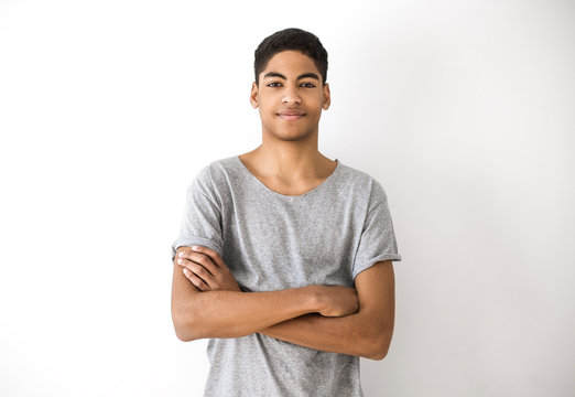 Portrait of an attractive young black man. Handsome afro american boy, teenager. Smiling guy with his hands on his chest on a white background. 