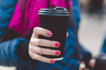 Close up of women hands holding paper cup of coffee