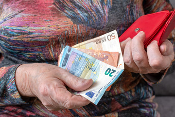 Hands of an elderly pensioner holding leather wallet with euro currency money. Concept of financial security in old age.