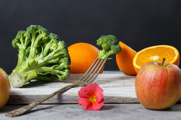 Diet mixed fruits and vegetables on a wooden board over black background with space for text