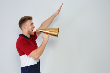 Young man with megaphone on light background. Space for text