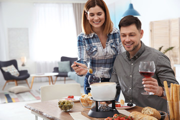 Happy couple enjoying fondue dinner at home