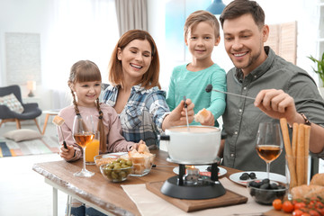 Happy family enjoying fondue dinner at home
