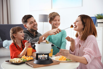 Happy family enjoying fondue dinner at home