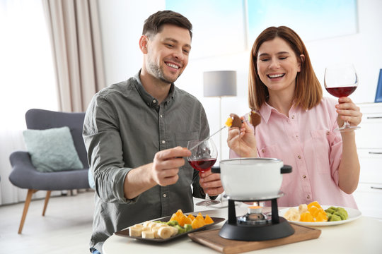 Happy Couple Enjoying Fondue Dinner At Home