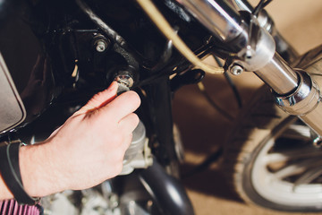 Obraz na płótnie Canvas Man fixing bike. Confident young man repairing motorcycle near his garage.ignition