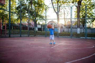 Little preschool girl playing basketball on court