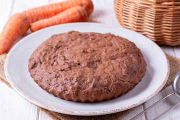 Chocolate cake with carrots in a bowl on a wooden table