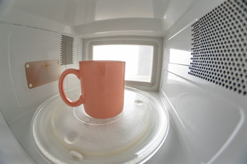 A mug standing on a microwave plate. Device for heating dishes with the use of myocual waves.
