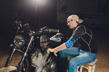 Fototapeta na wymiar Man fixing bike. Confident young man repairing motorcycle near his garage.