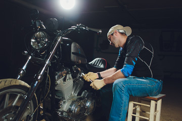 Naklejka na ściany i meble Man fixing bike. Confident young man repairing motorcycle near his garage.