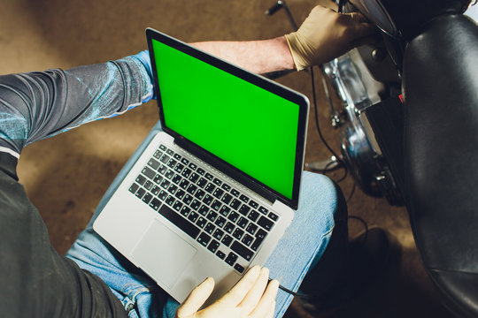 motorcycle mechanic repairing engine under supervisors guidance. video camera, laptop to view the inside of the engine to check soot. - Powered by Adobe