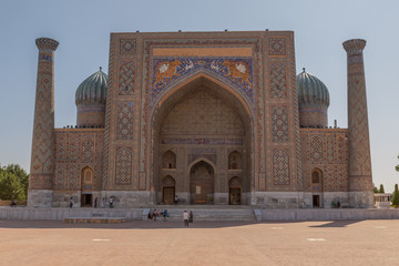 Sher-Dor madrassah on the Registan square in Samarkand. Area in Uzbekistan with the old madrasa. Sunny summer day in an ancient city in Central Asia.