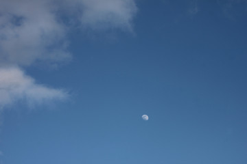 Blue sky with white clouds and white moon