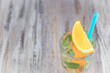 Citrus refreshing drink in a glass goblet on a wooden table. summer refreshing cocktail. Healthy food, drinks. orange and mint ice water. Copy space. horizontal view.