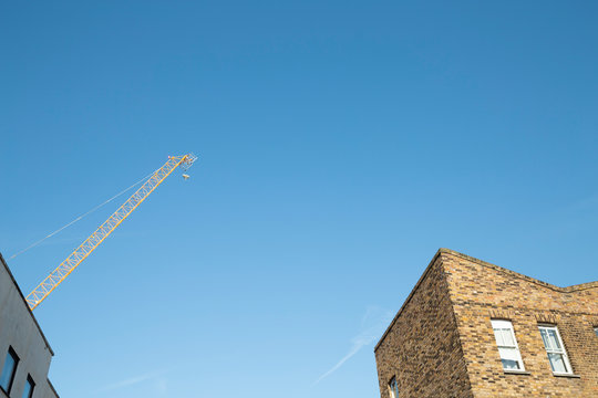 Building crane, top of the house and clear blue sky