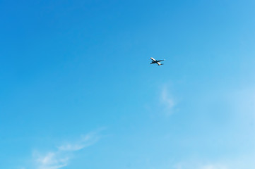 High in the sky is an airplane. An airplane in the blue sky.