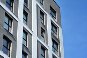 Multistory new modern apartment building. Stylish living block of flats. Modern, new executive apartments and with deep blue summer sky