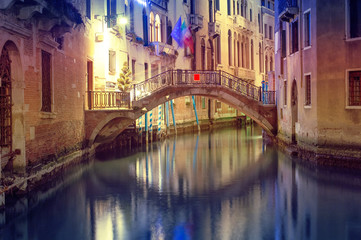 Venice canal view at night with bridge and historical buildings. Italy