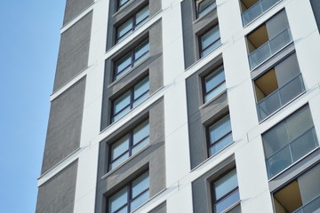 Fototapeta premium Multistory new modern apartment building. Stylish living block of flats. Modern, new executive apartments and with deep blue summer sky