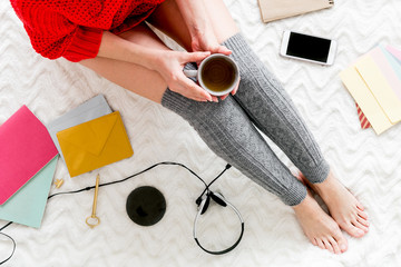 Girl top view with mobile phone, headphones, tea and notebook for work at home on bed background