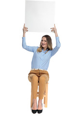 attractive smart casual woman holds white board in the air
