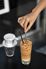 Fototapeta na wymiar Girl stirs iced coffee drink with spoon in outdoor cafe