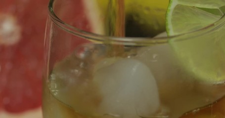 Pour whiskey, cognac, liqueur from a bottle into a glass cup. Close-up