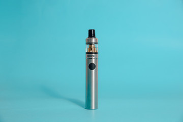Silver e-cigarette on a blue background. Concept of smoking cigarettes, quitting smoking cigarettes. Health damage caused by smoking. Problems with the lungs, lung cancer.