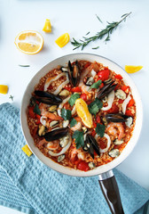 close-up of seafood paella and tomato sauce in a pan on a light background