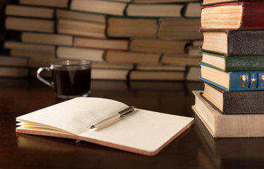 open notebook and cup on the background of books