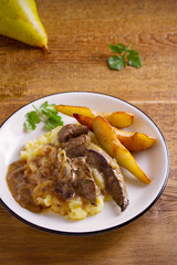 Liver with pears and cream and wine onion sause on mashed potato. vertical