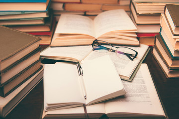 Open book and glasses on wood desk in the library room with blurred focus for education background and back to school concept