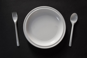 white tableware, plate spoon fork on black background
