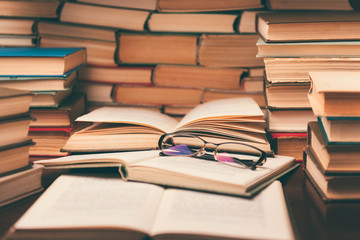 Open book and glasses on wood desk in the library room with blurred focus for education background and back to school concept