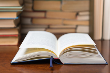 open book on the table, on the background of many books