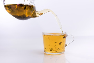 Roses Tea pouring into glass cup isolated on white