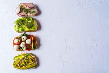 Sandwiches prepared with cream cheese ,vegetables and salmon, on a plate, over napkin. Healthy food for lunch or breakfast. Copy space, flat lay.