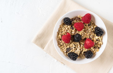 Organic granola with fresh berries on white background , flat lay.