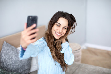 Beautiful young smiling woman with a phone in her hands takes a selfie.