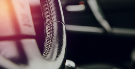 Close-up of the leather steering wheel in the car. Concept of car care, comfort in driving a car....