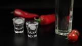 Cherry tomato roll up to two cups of vodka. Black background