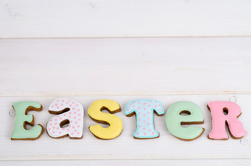 Creative greeting Happy Easter. Lettering from biscuits on white wooden background. Pastel holiday image.