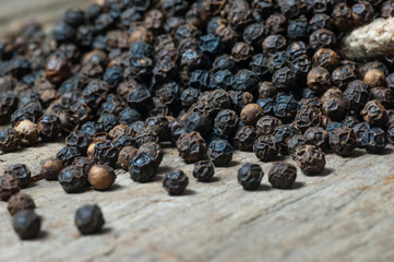 heap of black pepper corns, peppercorns on wooden background, dried spice pepper corn concept