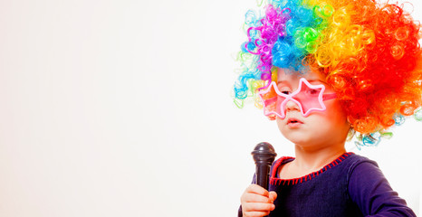 Famous actress. Humorous photo of cute child girl singing with a microphone