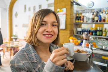 handsome girl drinking italian traditional short coffee espresso in a italian bar